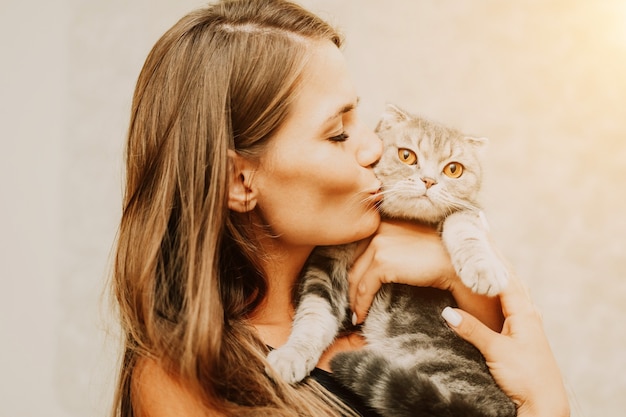 Attractive young woman with long hair embracing her pet with smile indoor portrait of cute woman