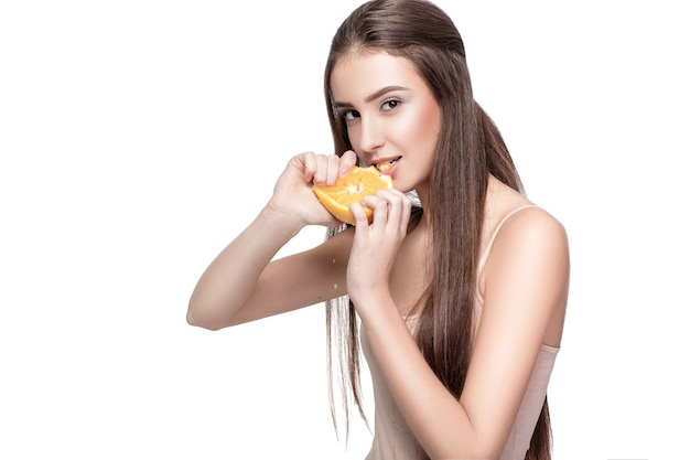 Attraente giovane donna con arancione isolato su sfondo bianco. cibo salutare