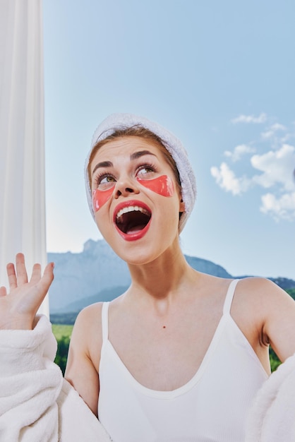 Attractive young woman with a towel on his head patches on his face stands on the balcony Perfect sunny morning