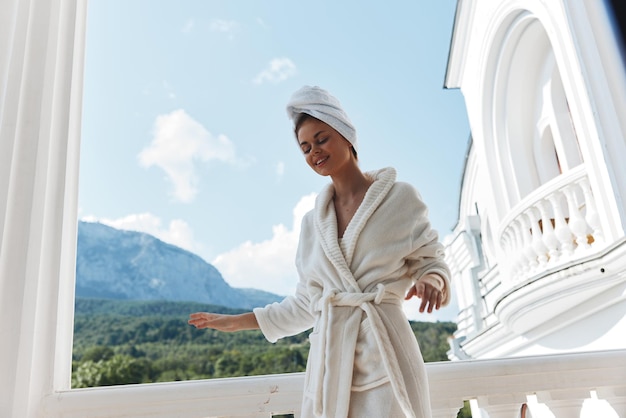 Привлекательная молодая женщина с полотенцем на голове в белом халате на балконе отеля Mountain View