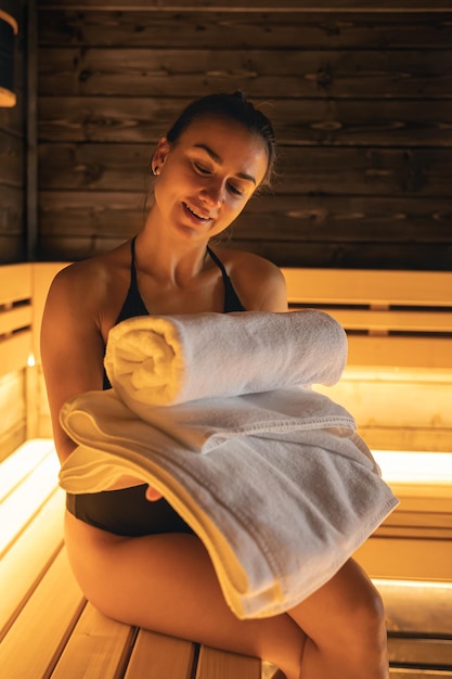 Attractive young woman with towels is relaxing in the sauna