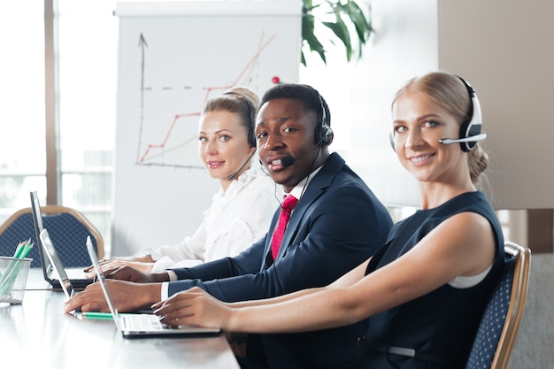 Attraente giovane donna che lavora in un call center con i suoi colleghi