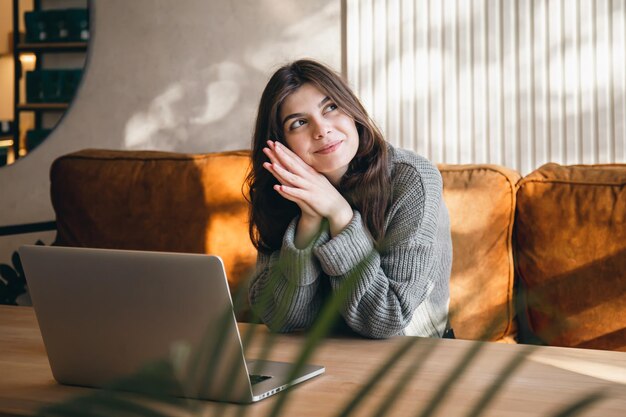 早朝にラップトップに取り組んでいる魅力的な若い女性