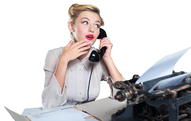 Attractive young woman working on vintage typewriter on white background