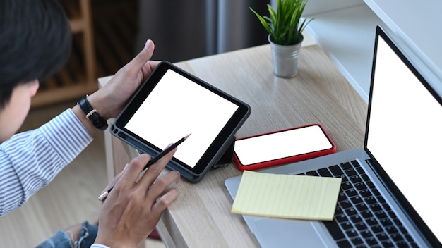 Attractive younng man working with multiple electronic internet devices at office.