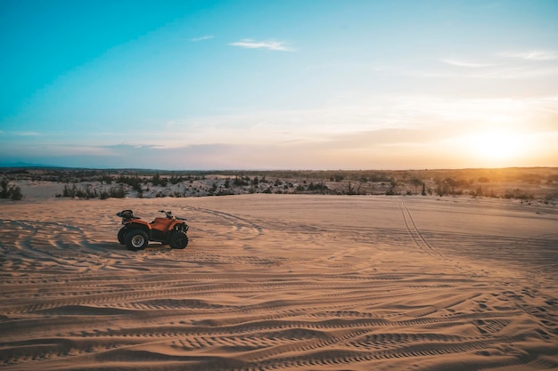 ATV Quad Bike in front of sunrise in the desert ATV stands in the sand on a sand dune in the desert of Vietnam MUI ne