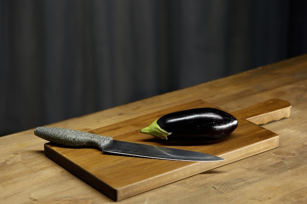 Aubergine en mes op een houten snijplank