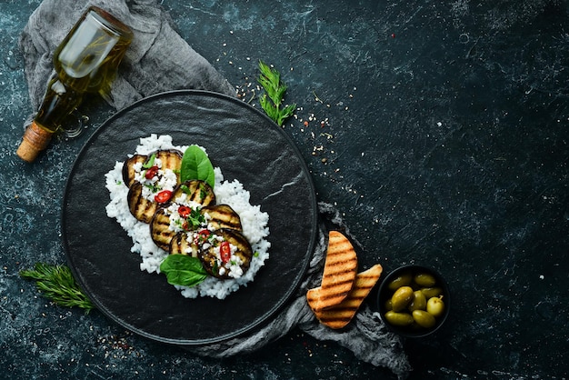 Aubergine gegrild met rijst en kaas op een zwarte plaat Bovenaanzicht Rustieke stijl