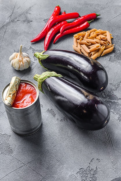 Aubergine penne ingredients eggplant pasta, pepper tomatoe sauce, on grey background side view.