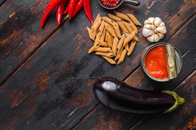 Aubergine penne ingredients eggplant pasta, pepper tomatoe sauce, on old dark wooden table top view space for text.