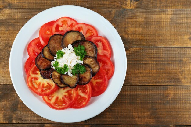 Auberginesalade met tomaten en fetakaas op houten achtergrond