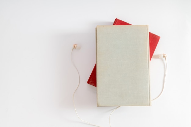 Audio book concept. Headphones and book over white table background.