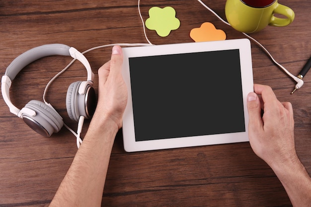 Foto concetto di audiolibro giovane uomo che utilizza tablet e cuffie da vicino