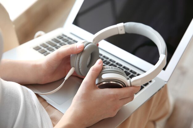 Audio book concept Young woman using laptop with headphones close up