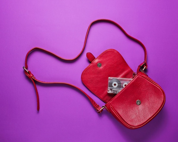 Audio cassette in a red leather bag on a purple background