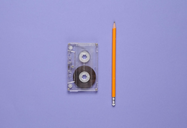 Audio cassette tape with pencil on a purple background 80s