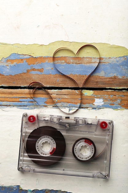 写真 木製の背景にハートの形をした磁気テープとオーディオカセット