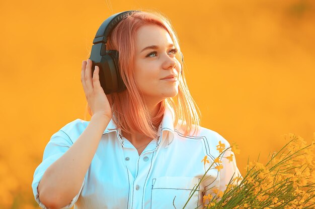 Foto cuffie audio estate ragazza musica in un campo di fiori, giovane femmina primavera