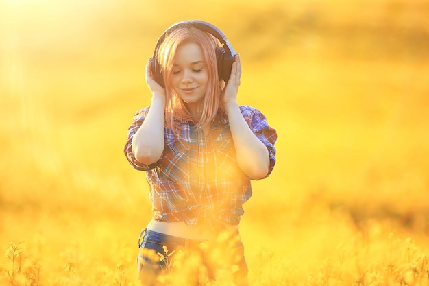 Cuffie audio estate ragazza musica in un campo di fiori, giovane femmina primavera