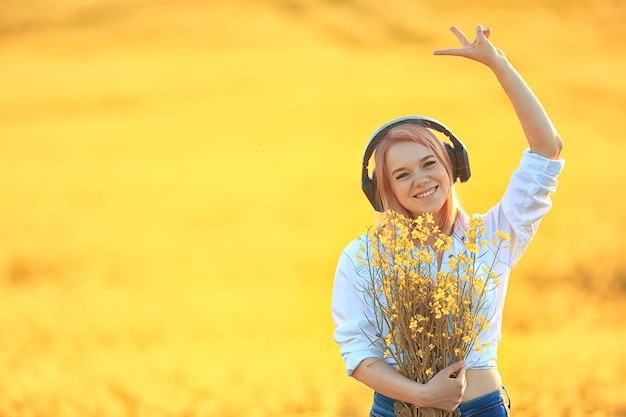 Foto audio koptelefoon zomer meisje muziek in een veld van bloemen, jonge vrouwelijke lente