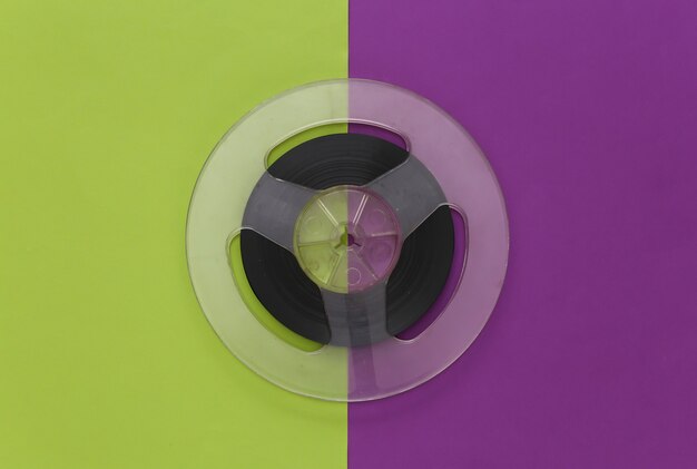 Audio magnetic tape. Film reel on a purple green. Retro style