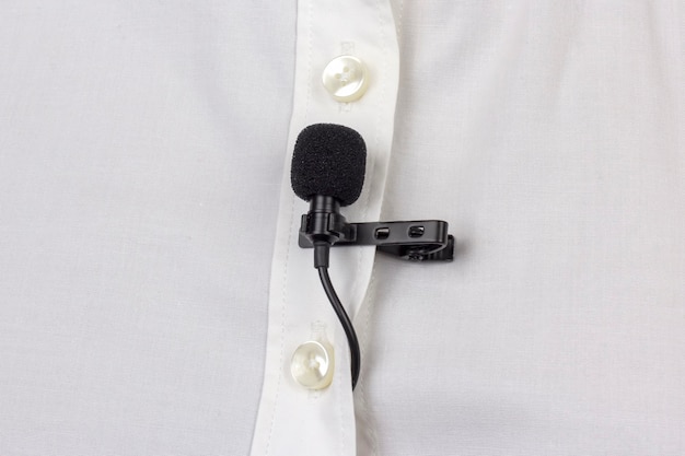 Audio-opname van het geluid van de stem op de condensatormicrofoon. de lavaliermicrofoon is bevestigd met een clip op een wit dameshemd close-up.