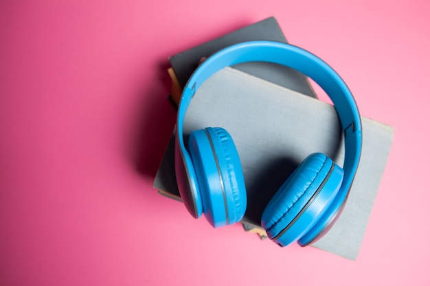 Audioboek-concept. boeken en koptelefoons op een roze achtergrond