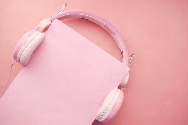 Audioboekconcept hoofdtelefoon en boek op roze achtergrond