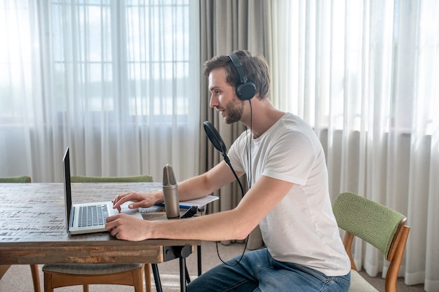 Audioconferentie. jonge, bebaarde man die in een koptelefoon zit en een audioconferentie heeft