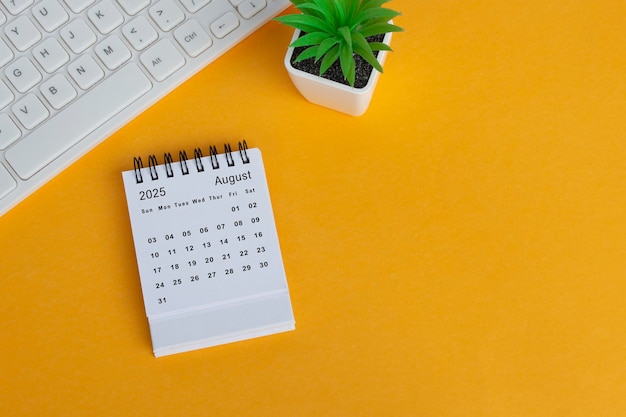 August 2025 desk calendar on yellow background directly above flat lay