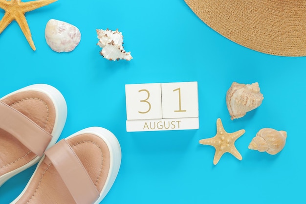 August 31 Wooden calendar on a blue background with summer accessories top view Vacation
