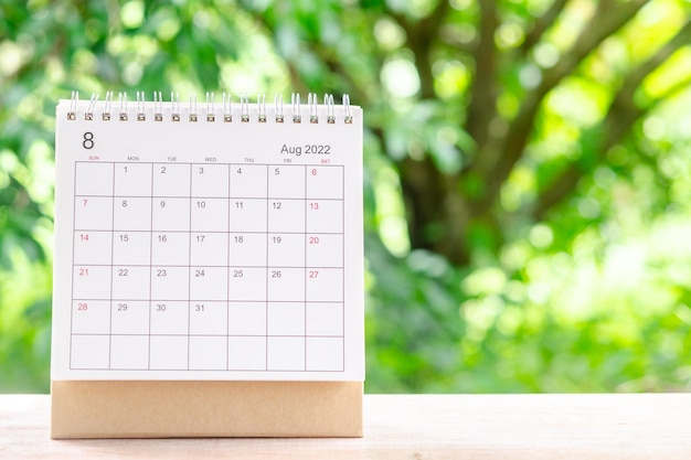 August month, Calendar desk 2022 for organizer to planning and reminder on wooden table with green nature background.