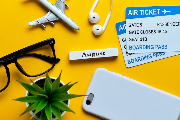 August vacation concept with airplane on top view yellow background
