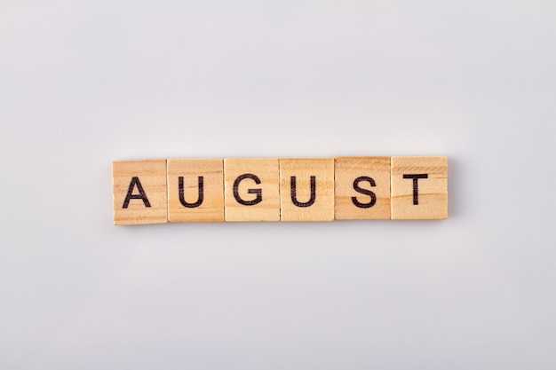 August word written on wooden blocks. Isolated on white background.