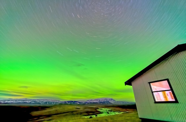 Aurora borealis lights river and house long exposure