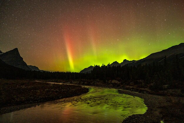 Foto aurora boreale sopra la montagna riflessa nel corso del ruscello aurore boreale