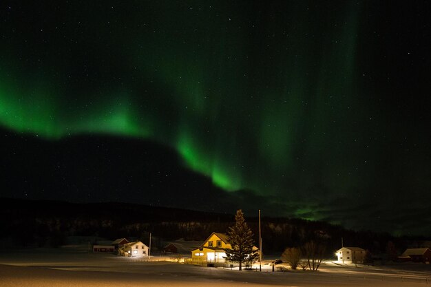 Photo aurora borealis in sky over illuminated houses