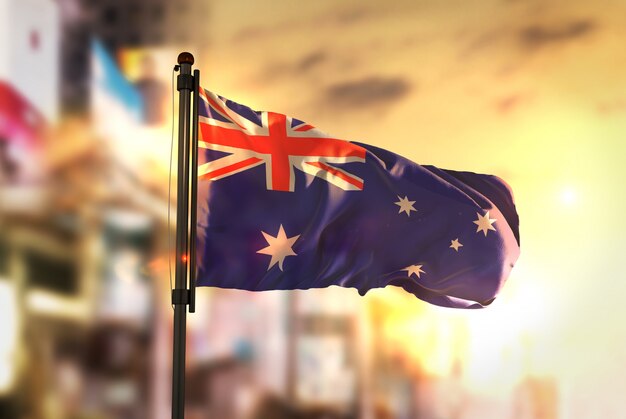 Australia Flag Against City Blurred Background At Sunrise Backlight