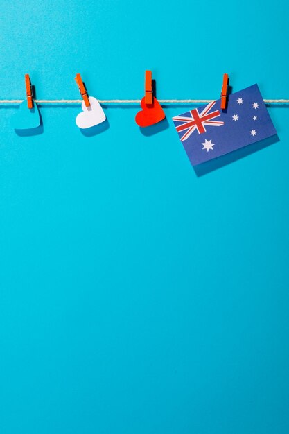 Australia flag and heart shapes hanging on clothesline with copy space against blue background. patriotism, symbol and identity