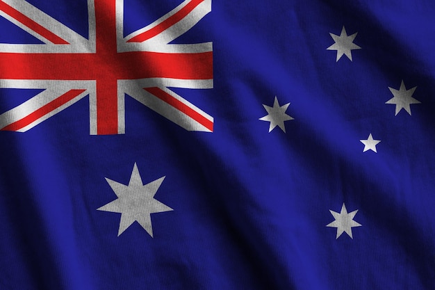 Australia flag with big folds waving close up under the studio light indoors The official symbols and colors in banner