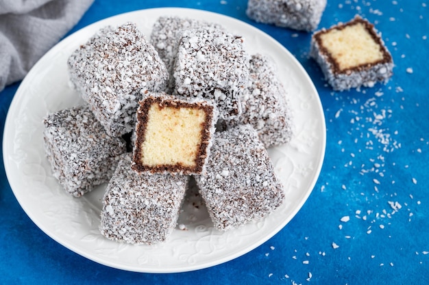 Foto torta lamington australiana con glassa al cioccolato e scaglie di cocco con una tazza di tè messa a fuoco selettiva