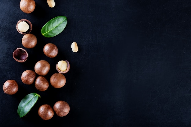 Australian peeled and whole macadamia nut with green leaves on black background