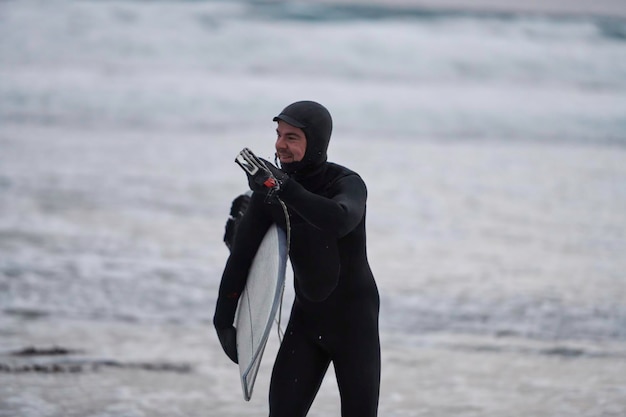 Authentic local Arctic surfer going by beach after surfing in Northern sea. Norwegian sea coastline. Winter water activities extreme sport