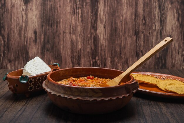 Authentic mexican chicken tinga typical mexican food prepared in a clay pot on a wooden table