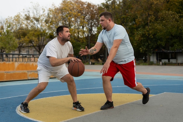 Foto scene autentiche di maschi di taglia plus che giocano a basket