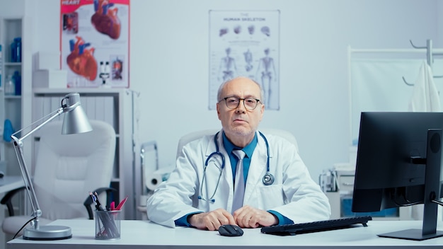 Authentic senior doctor making an online consultation via zoom call. Modern technology and internet healthcare. Old experienced practitioner talking with patients using tech and web