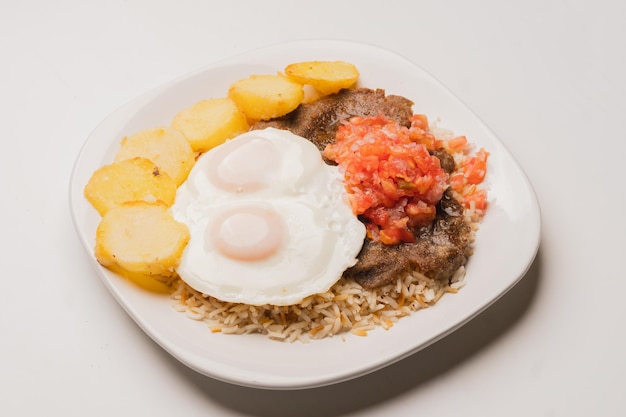 Authentic traditional Bolivian meal Silpancho made of beef potatoes rice fried eggs tomato an