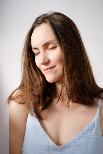 Authentiek portret van blanke brunette vrouw met gesloten ogen zonder make-up in blauw T-shirt volwassen vrouw verticale natuurlijke schoonheid