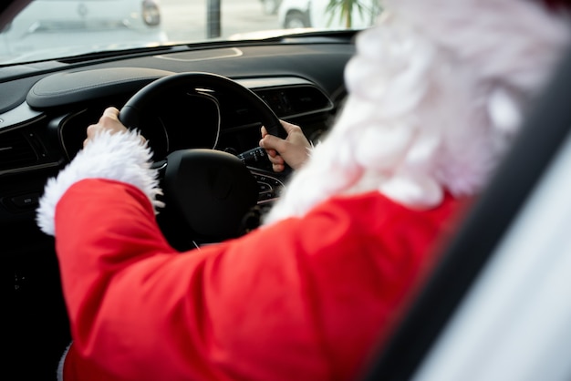 Authentieke kerstman die buiten in zijn moderne auto rijdt