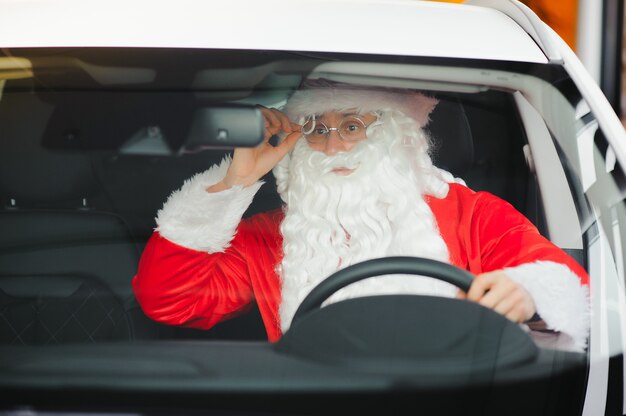 Authentieke kerstman die buiten in zijn moderne auto rijdt